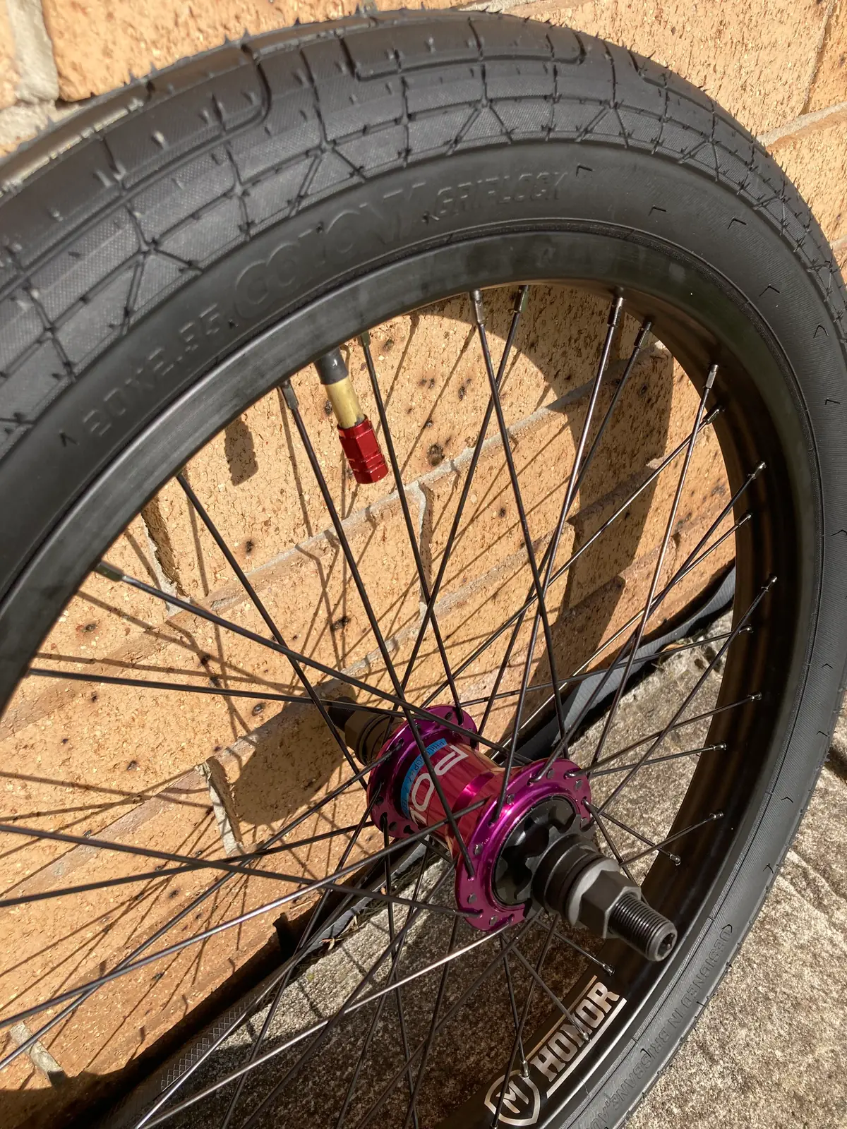 A purple anodised hub laced to a black rim with a tan-wall tyre
