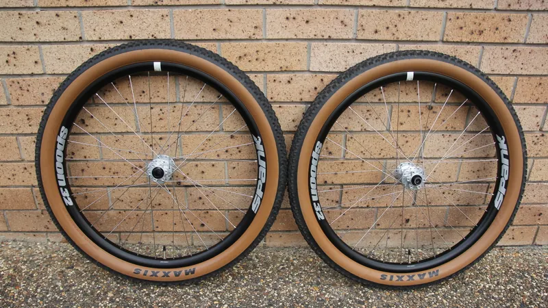 A pair of finished dirt jump wheels with tan-wall tyres, leaning against a brick wall